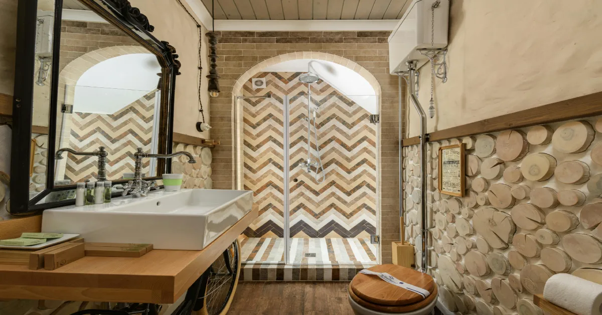 Rustic DIY bathroom makeover with chevron pattern shower tiles, wooden vanity, and decorative log wall feature