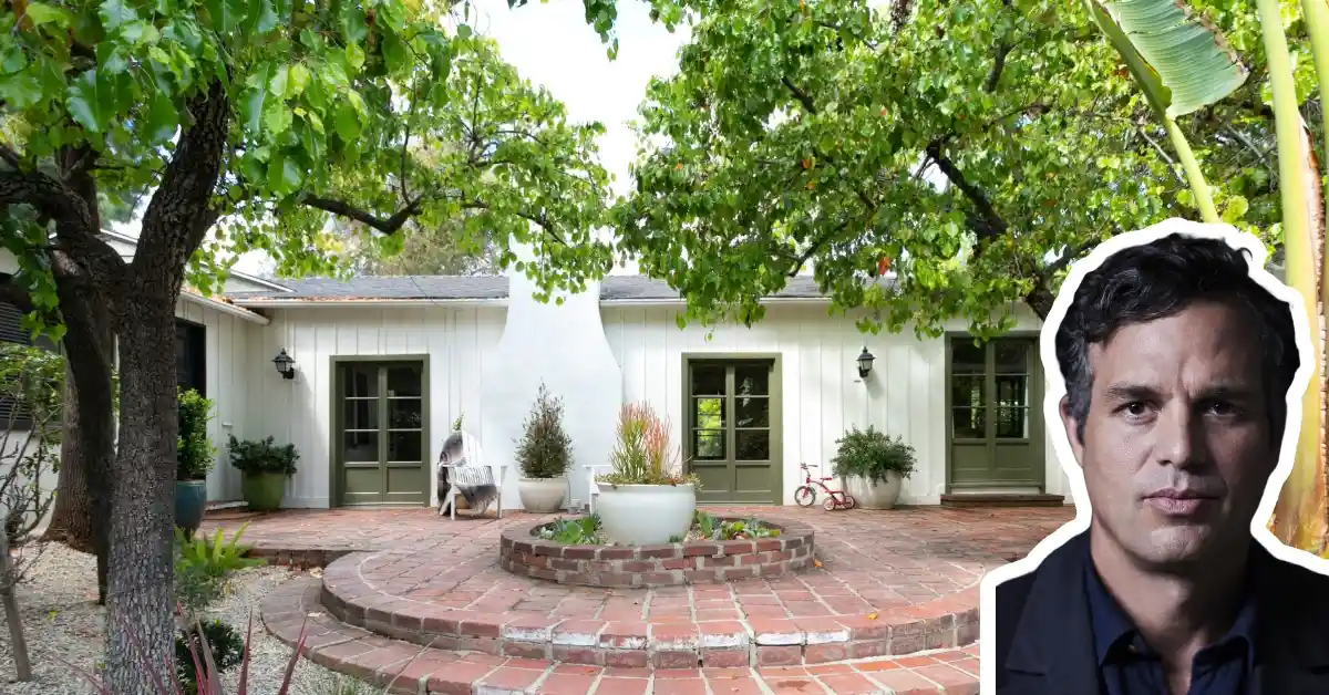 Mark Ruffalo house exterior showing white single-story home with brick patio, mature trees, and green shuttered windows in Hollywood Hills