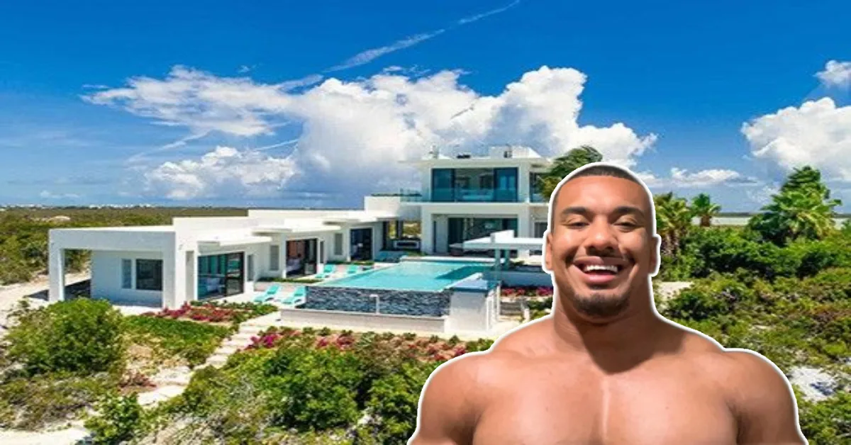 Larry Wheels House front view with Larry smiling shirtless in front of his luxurious modern beachfront mansion under a bright tropical sky.